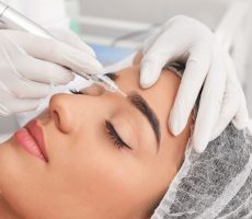 Young woman undergoing procedure of permanent eyebrow makeup in tattoo salon, closeup